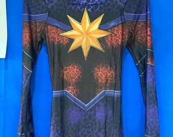 May include: A purple and black bodysuit with a gold star on the chest. The bodysuit has a leopard print pattern.