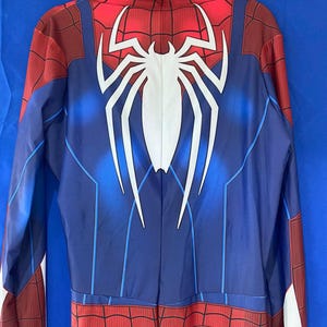 May include: A blue and red Spiderman costume with a white spider logo on the back. The costume has a zipper down the back.