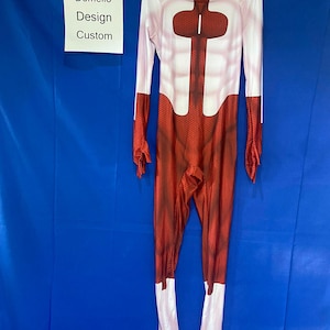 Puede incluir: Traje de cuerpo entero rojo y blanco con un patr&oacute;n de panal. El traje tiene cuello alto y mangas largas. El traje est&aacute; hecho de un material el&aacute;stico. El traje tiene un panel de pecho blanco con un patr&oacute;n de panal rojo. El traje tiene un panel blanco en las piernas. El traje est&aacute; colgado en una percha. El texto "Domello Design Custom" est&aacute; en una etiqueta blanca.