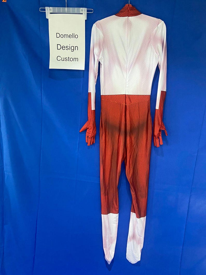 Puede incluir: Un traje de cuerpo entero rojo y blanco con un patr&oacute;n texturizado. El traje tiene mangas largas y cuello alto. El traje est&aacute; hecho de un material el&aacute;stico. "Domello Design Custom" est&aacute; escrito en un cartel blanco.
