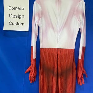Puede incluir: Un mono de spandex rojo y blanco con un patr&oacute;n de panal en las piernas. El mono tiene mangas largas y cuello alto. El texto "Domello Design Custom" est&aacute; escrito en una hoja de papel blanca.