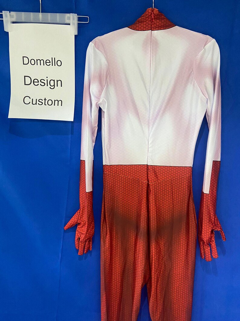 Puede incluir: Un mono de spandex rojo y blanco con un patr&oacute;n de panal en las piernas. El mono tiene mangas largas y cuello alto. El texto "Domello Design Custom" est&aacute; escrito en una hoja de papel blanca.