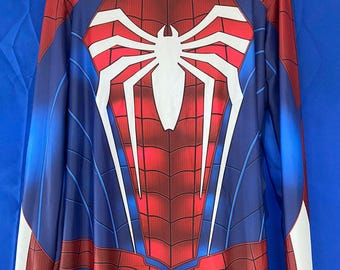 Puede incluir: Un disfraz de Spiderman rojo y azul con un logotipo de araña blanco en el pecho. El disfraz tiene una cremallera en la espalda y mangas largas.