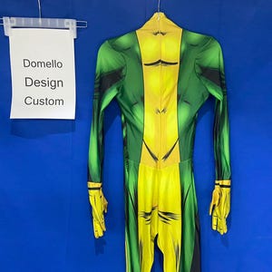 Op de afbeelding: Groen en geel spandex bodysuit met een bedrukt ontwerp. Het pak heeft een rits aan de achterkant en een label met de tekst "Domello Design Custom".