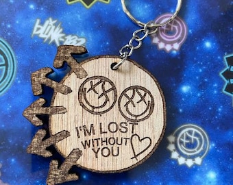 May include: Wooden keychain with a brown background and a black and white smiley face design. The text "I'm lost without you" is written on the keychain with a heart symbol.