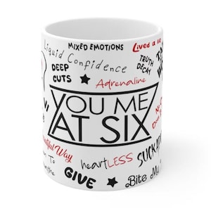 May include: White ceramic mug with black text that reads "You Me At Six" surrounded by other black text including "Mixed Emotions", "Confidence", "Adrenaline", "Heartless", "Suckers", "Give", and "Bite My".