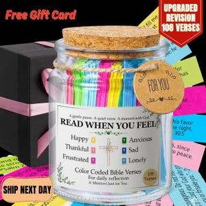 May include: A glass jar containing colourful Bible verses, with a cork lid and a "For You" tag. A black gift box with a pink ribbon is also present. The jar's label says "Read When You Feel".