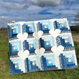 Könnte beinhalten: Eine blaue und weiße Steppdecke mit einem Blockhausmuster. Die Steppdecke besteht aus verschiedenen Blautönen und ist mit weißem Garn gesteppt.