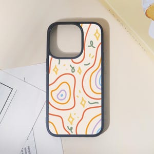 May include: A navy blue phone case with a cream-colored background and a colorful abstract design. The design features orange, red, and purple wavy lines, along with yellow stars and green swirls. The case has a smooth finish.