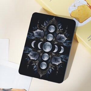 May include: A black rectangular phone case with a celestial design. The design features phases of the moon, surrounded by blue floral elements. The case has a glossy finish and rounded edges.
