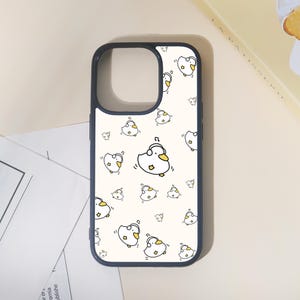May include: A phone case with a navy blue border and a cream-colored background. The case is covered in a pattern of cartoon ducks wearing headphones. The ducks are white with yellow beaks and feet, and black outlines.