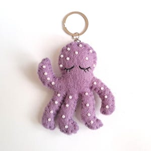 Op de afbeelding: Paarse vilten octopus sleutelhanger met witte stippen en geborduurde ogen.