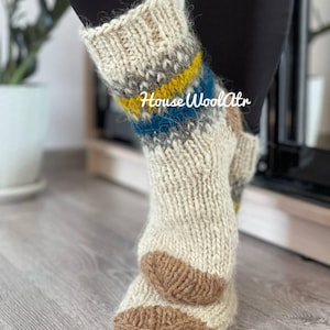 May include: White wool socks with brown, blue, and yellow stripes. The socks are knitted and have a fuzzy texture. The text "House Wool Attr" is visible on the socks.