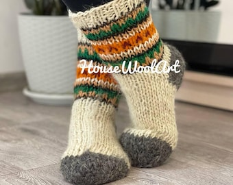 May include: A pair of white wool socks with a green, orange and brown striped pattern. The socks have a grey wool toe and heel.
