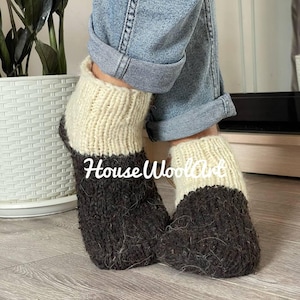 Könnte beinhalten: Handgestrickte Wollsocken in Zweifarben-Design. Der obere Schaft ist cremefarben, während der Fußbereich dunkelbraun ist. Der Text "House WoolArt" ist sichtbar. Die Socken werden mit blauen Jeans getragen.