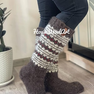 May include: A pair of brown wool socks with a patterned design in white and red. The socks are knee-high and have a textured appearance. The text "HouseWoolArt" is visible on the socks.