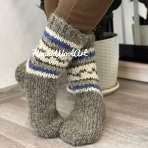 May include: Pair of gray wool socks with blue and white stripes. The socks are knitted and have a fuzzy texture.