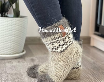 May include: Hand-knitted wool socks in shades of gray, beige, and white. The socks feature a patterned design around the ankle and a leather tag. The text "House Wool Art" is visible on the socks.