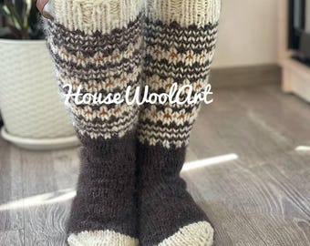 May include: Knee-high knitted socks in shades of brown, cream, and tan. The socks feature a patterned design and are worn over black leggings. The text "House WoolArt" is visible on the socks.