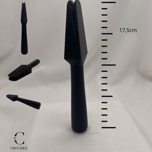 Puede incluir: Una herramienta de ganchillo negra, de aproximadamente 17,5 cm de largo, con un diseño puntiagudo único. La imagen muestra la herramienta desde múltiples ángulos, incluido un primer plano. La herramienta está etiquetada con el texto "CROCHEZ France".
