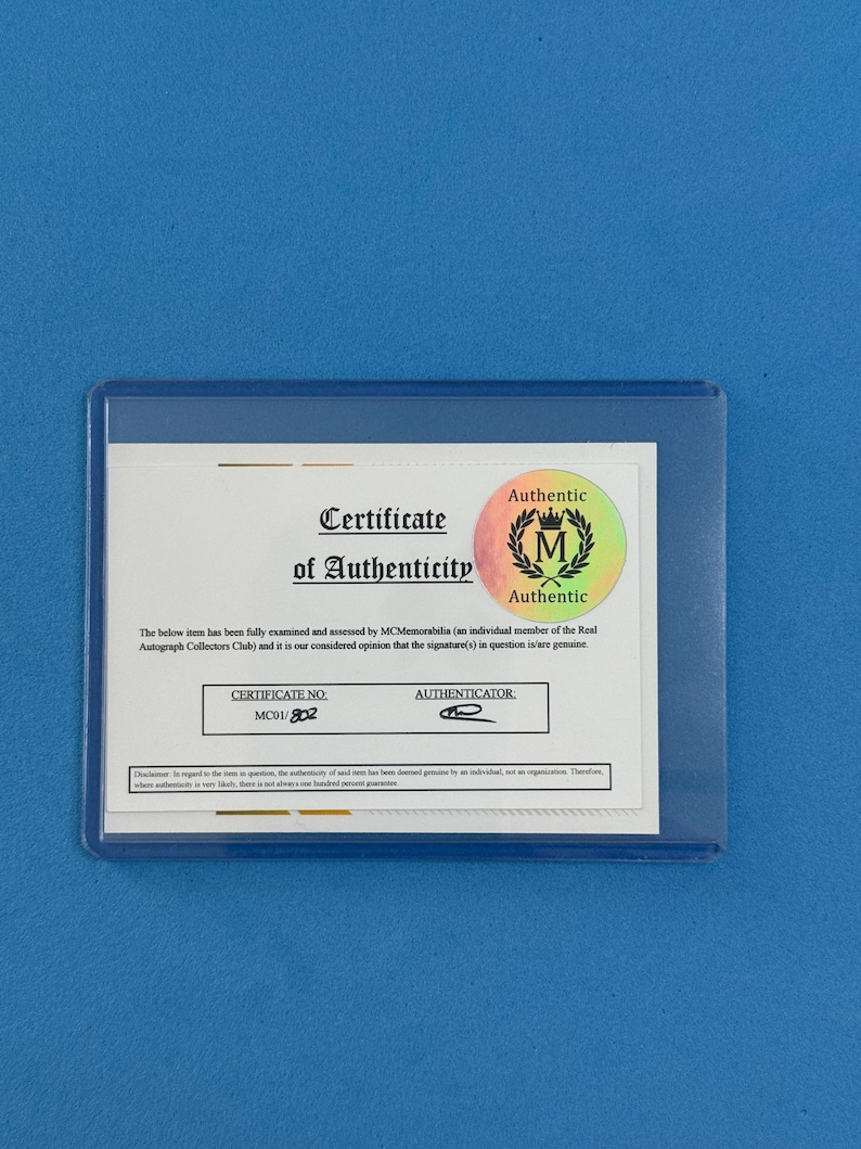 Peut inclure: Un certificat d'authenticit&eacute; dans une pochette en plastique transparent. Le certificat porte le texte "Certificate of Authenticity" et un sceau "Authentic". Le num&eacute;ro de certificat est MC01/802.