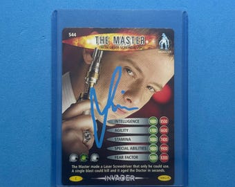 May include: A trading card of "The Master" with a laser screwdriver, signed in blue ink. The card features a monster graphic and includes statistics for intelligence, agility, stamina, special abilities, and fear factor. The card is in a protective sleeve.