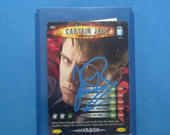 May include: A Captain Jack trading card from the Invader series, with an autograph. The card shows a portrait of the character and includes statistics like Agility and Fear Factor. The card is protected in a clear sleeve.