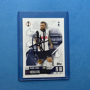May include: A Topps trading card featuring Pierre-Emile Højbjerg in a white and navy soccer uniform. The card has a blue border and is encased in a protective sleeve. The card includes the UEFA Europa League logo and player stats.