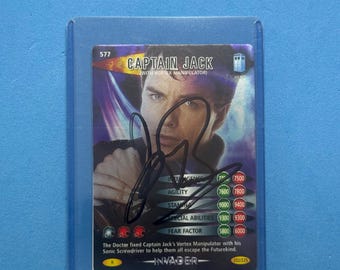 May include: A Captain Jack trading card, featuring a portrait of the character with the text "CAPTAIN JACK" and "INVADER". The card is encased in a protective sleeve. The card has a signature on it.
