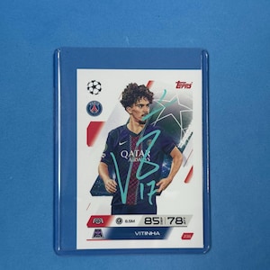 Pode incluir: Um cartão colecionável Topps com o jogador de futebol Vitinha em uma camisa azul e branca com o logotipo da Qatar Airways. O cartão está em uma manga protetora. O logotipo da Topps e o logotipo do Paris Saint-Germain estão presentes.