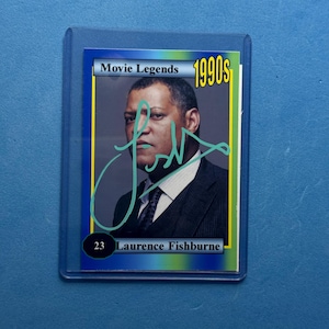 Op de afbeelding: Een verzamelkaart met Laurence Fishburne uit de jaren 1990. De kaart is gemarkeerd als "Movie Legends" en bevat een turquoise handtekening. De kaart zit in een beschermhoes.