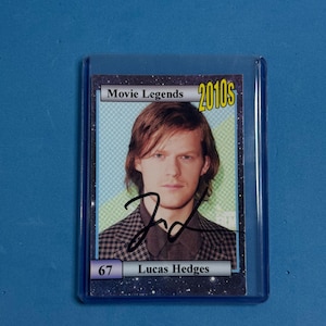 May include: A trading card featuring Lucas Hedges from the 2010s Movie Legends series. The card has a portrait of the actor with his signature. The card is encased in a protective plastic sleeve.