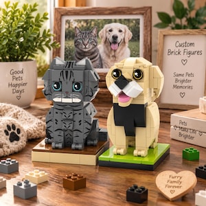 May include: A grey tabby cat and a tan dog constructed from interlocking plastic building bricks. The cat sits on a brown base, and the dog sits on a green base. Both figures feature large black eyes and are displayed on a wooden surface.