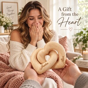 Puede incluir: Dos esculturas de madera en forma de corazón entrelazadas con un acabado de veta de madera clara. El corazón izquierdo tiene grabado el nombre Justin y el derecho el nombre Alice. El texto A Gift from the Heart aparece en la esquina superior.