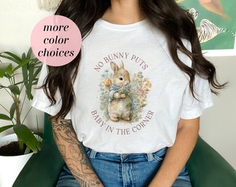 May include: White t-shirt with a graphic of a bunny rabbit and the text "No bunny puts baby in the corner".