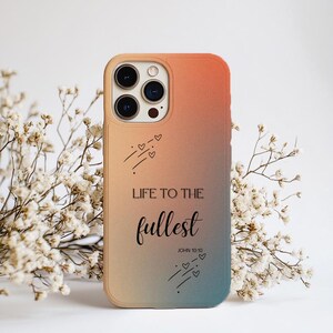 Puede incluir: Una taza de cerámica blanca con un asa negra y el texto "But First, Coffee" en negrita negra. La taza está sobre un fondo borroso. La taza mide aproximadamente 10 cm de altura.