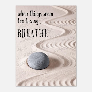 Puede incluir: Una cita motivacional, "when things seem too taxing... breathe", está impresa sobre un fondo blanco con una piedra gris sobre una superficie arenosa con un patrón de líneas.