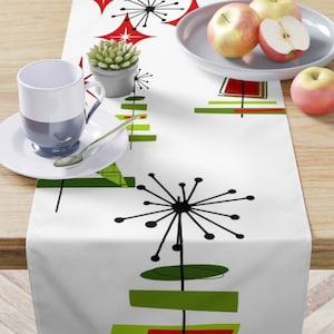 May include: White table runner with a mid-century modern design featuring green and red geometric shapes and black stylized trees.