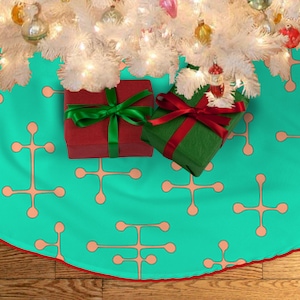 Könnte beinhalten: Ein türkisblauer Christbaumrock mit einem sich wiederholenden Muster aus pfirsichfarbenen abstrakten Formen. Zwei verpackte Geschenke mit rotem und grünem Band liegen auf dem Rock.