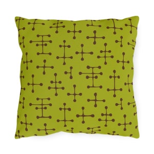 May include: Square throw pillow with a lime green background and a repeating pattern of brown, stylized atomic shapes. The pillow has a soft, textured appearance and is likely made of fabric.