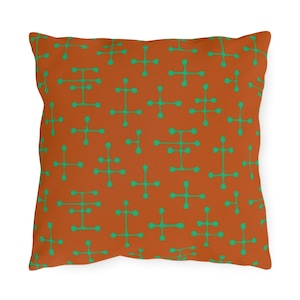 May include: A square throw pillow with a rust-colored background and a repeating pattern of green abstract shapes.