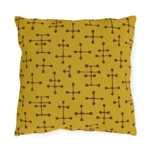 May include: A yellow throw pillow with a brown geometric pattern. The pattern is made up of small circles and lines that form a repeating design.