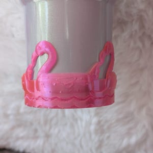 May include: A pink plastic cup with a pink flamingo design around the rim.