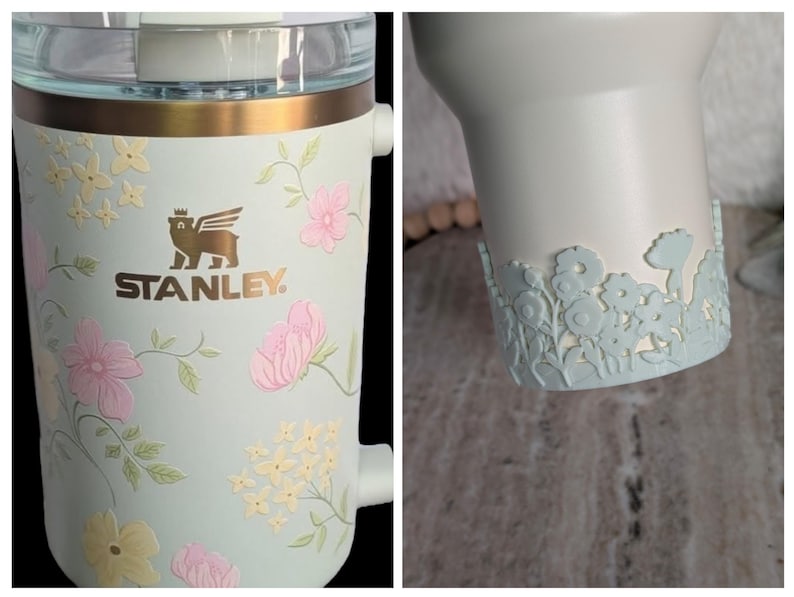 May include: A light blue Stanley tumbler with a floral design. The tumbler features pink and yellow flowers with green leaves. The Stanley logo is in gold. The bottom of the tumbler has a light blue floral cut-out design.