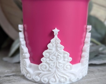 May include: White, decorative, Christmas tree-shaped cup holder with a pink cup inside.