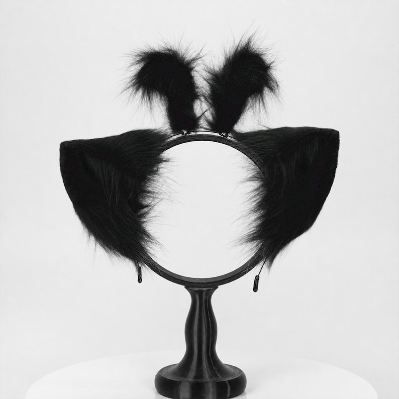 May include: A black headband featuring two large, pointed, faux fur cat ears attached to the sides and two smaller, upright, fluffy faux fur tufts positioned at the top center of the thin, circular black band frame.