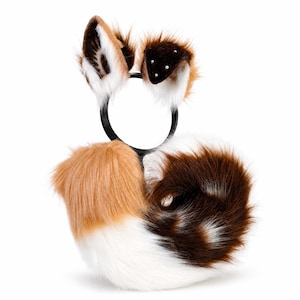 May include: A black headband featuring two upright faux fur ears in shades of brown, white, and black, with small white accents on the right ear. Attached to the base of the headband is a large, curled faux fur tail in a mix of brown, white, and black.