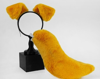 May include: A set of bright yellow faux fur animal ears attached to a thin black headband and a matching yellow faux fur tail with a white elastic attachment loop. The ears and tail are displayed on a black stand with a circular top.