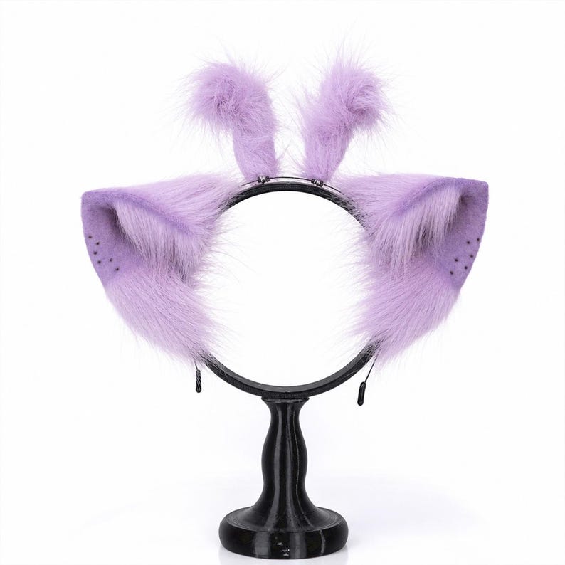 May include: A black headband featuring two large, pointed, lavender-colored faux fur animal ears and two smaller, upright, fluffy lavender faux fur tufts on top. The ears have a subtle dotted pattern near the outer edges and long, soft fibers.