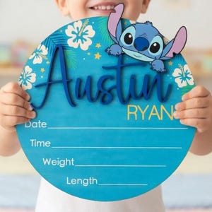 Peut inclure: Un panneau de naissance rond en bois bleu orné d'un personnage de dessin animé, de fleurs d'hibiscus blanches et de feuilles de palmier vertes. Le prénom Austin est en relief bleu foncé, Ryan en jaune, avec des lignes pour Date, Heure, Poids, Taille.